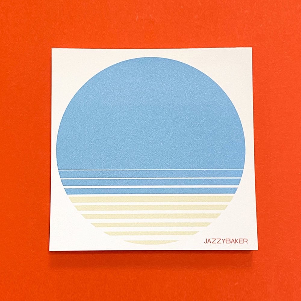 Quadratisches Memopad Beach vor rotem Hintergrund. Ein blauer Kreis mit unterem Teil in Gelb stellt das Meer und den Strand dar.